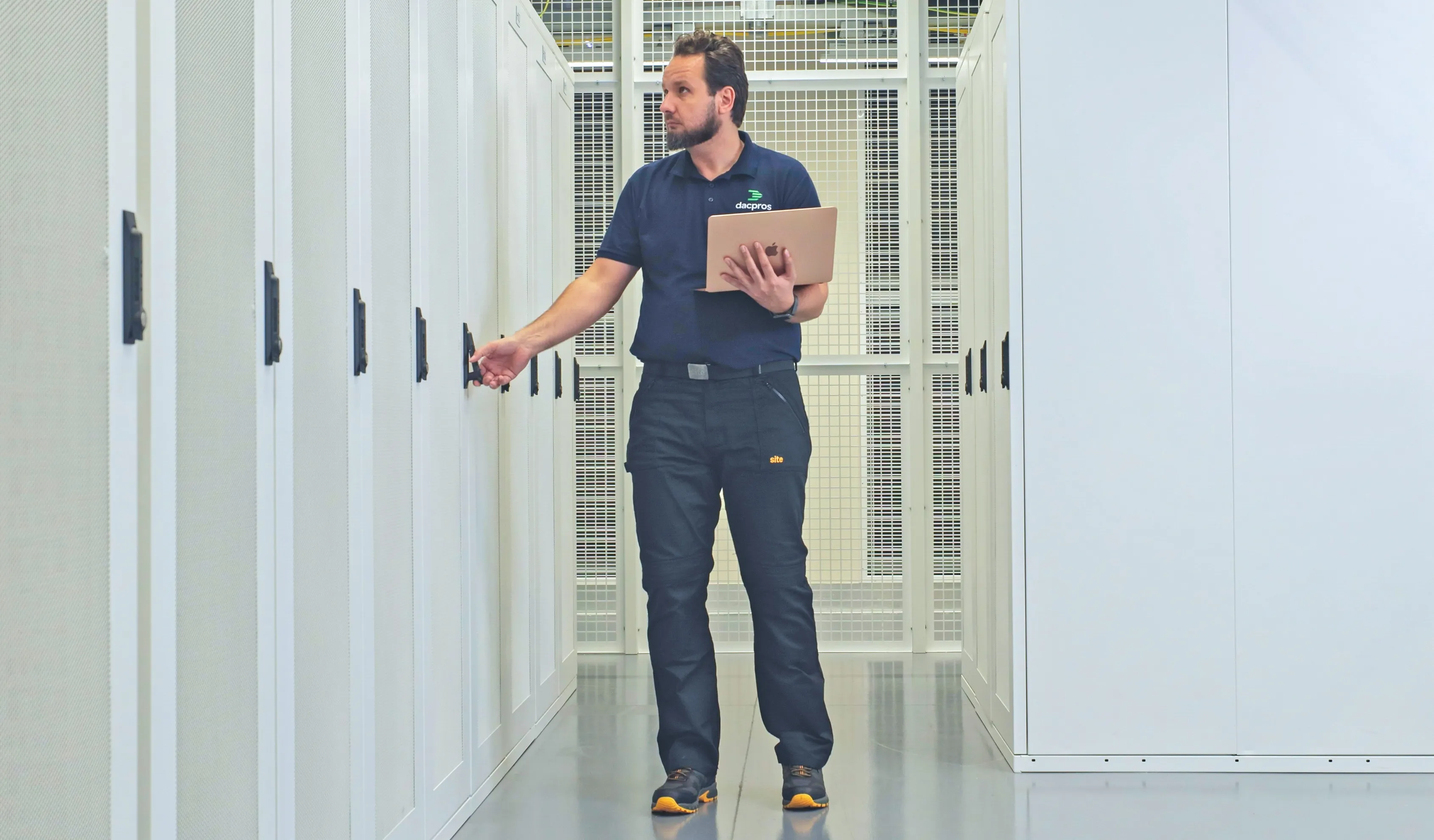DACPROS engineer with tablet conducting an inspection walk through data centre aisle