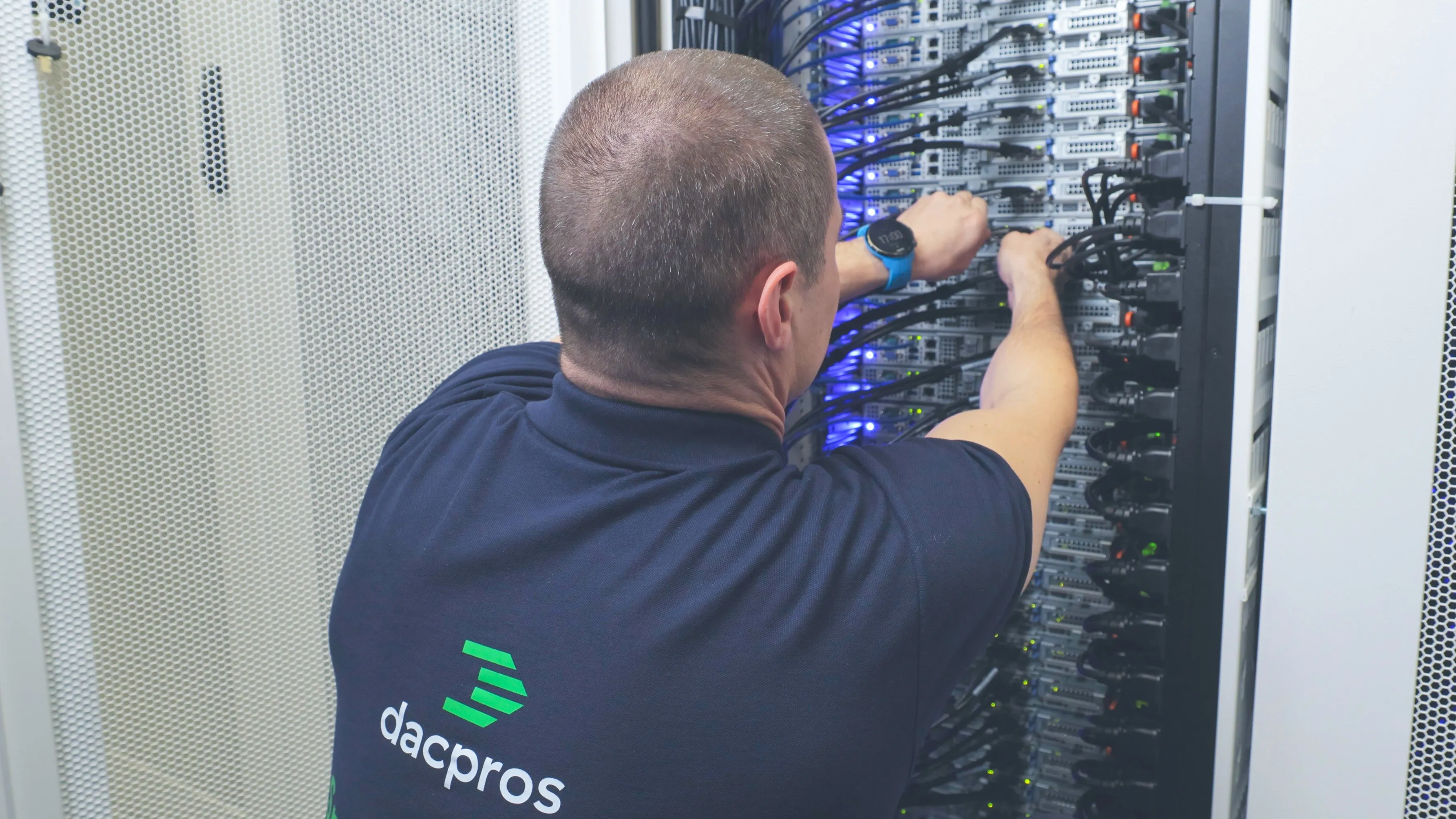 DACPROS engineer patching cables into an open rack at a data centre