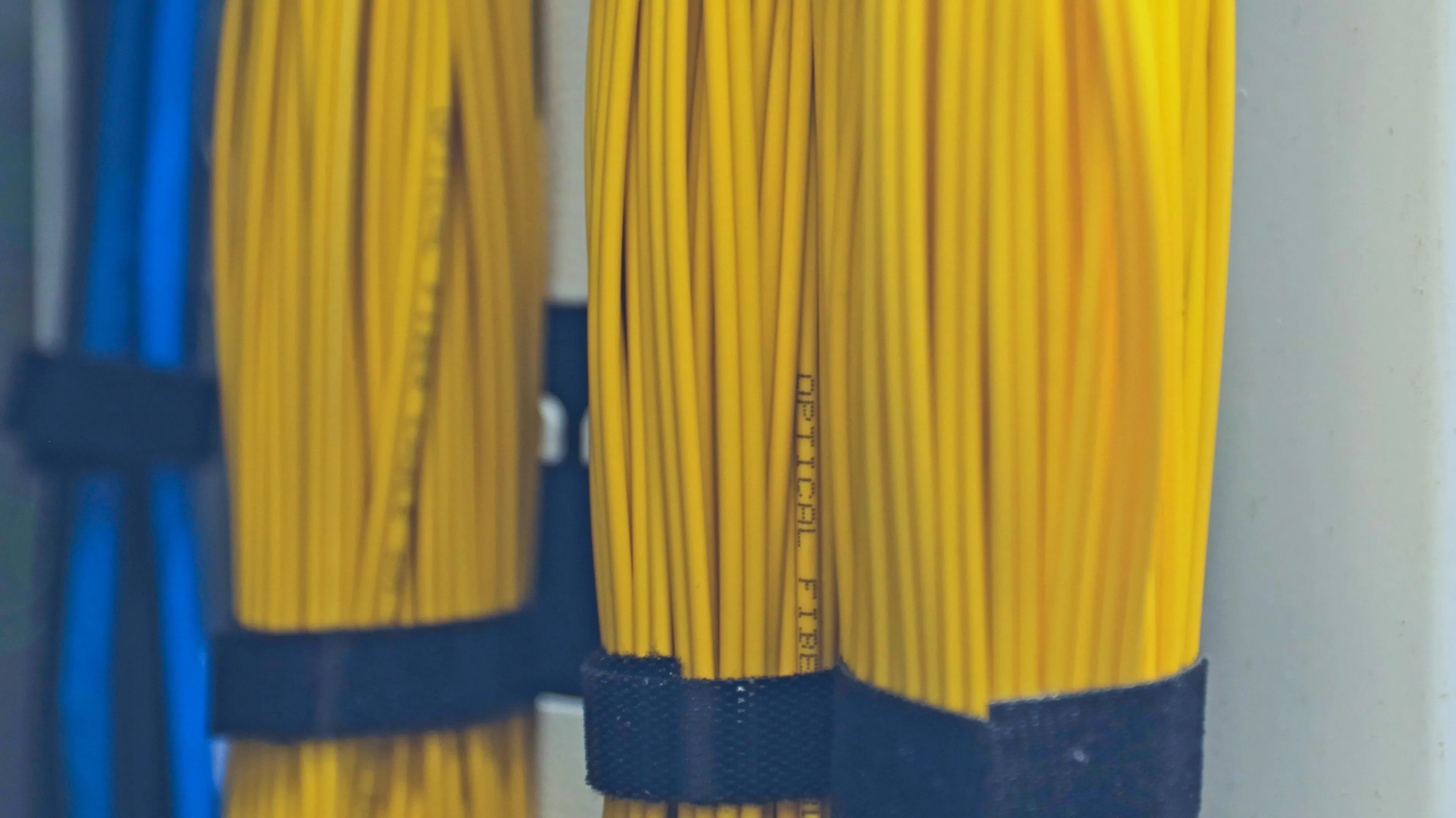 Neatly bundled yellow fibre runs secured with velcro ties — colour-coded structured cabling dressed to standard.
